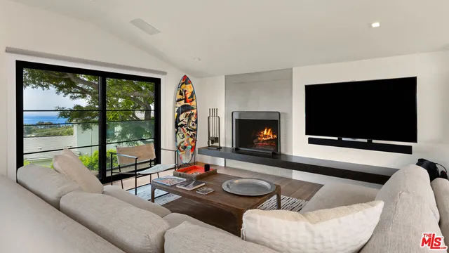 a living room with furniture floor to ceiling window and a flat screen tv
