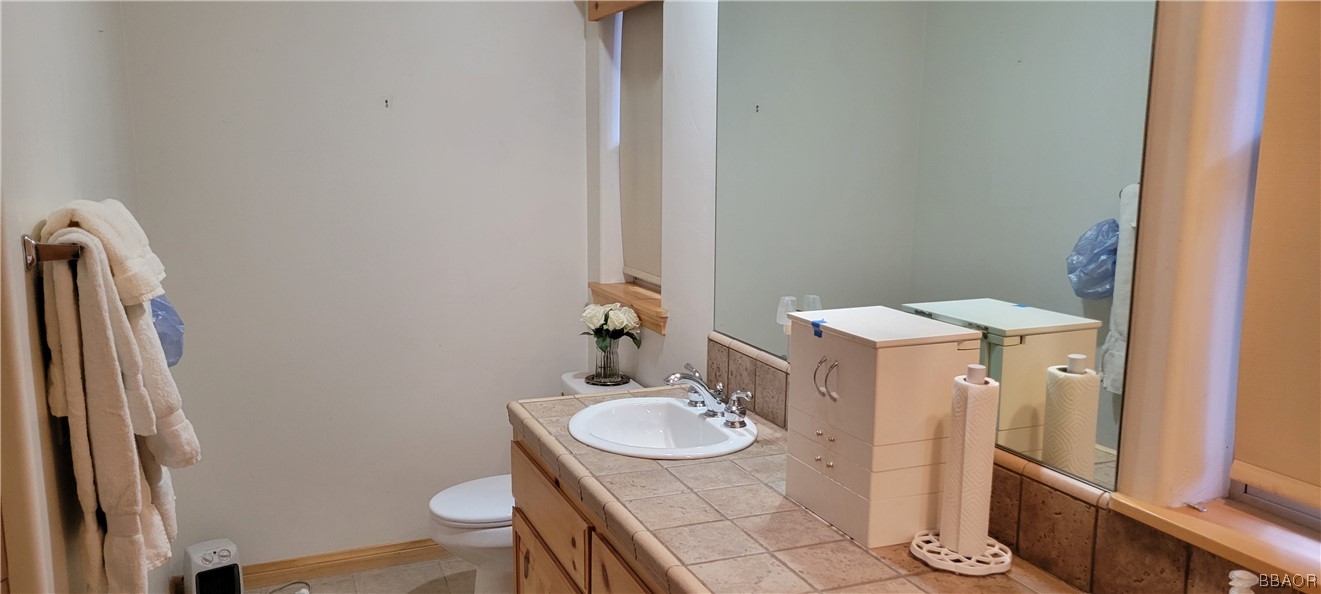 1685 Angels Camp Road Big Bear City, CA 92314 - Photo 14 of 35 a bathroom with a granite countertop sink a toilet a mirror and shower
