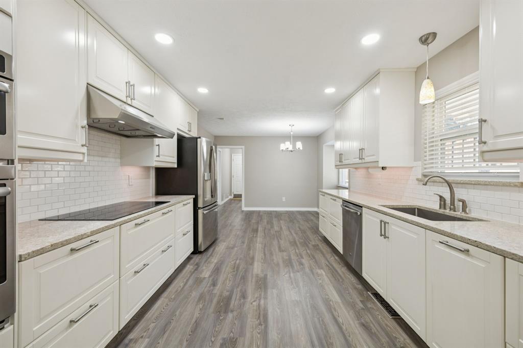 9536 Millridge Drive Dallas, TX 75243 - Photo 10 of 33 a large kitchen with stainless steel appliances granite countertop a lot of counter space and wooden floors