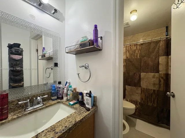 a bathroom with a granite countertop sink a toilet and shower