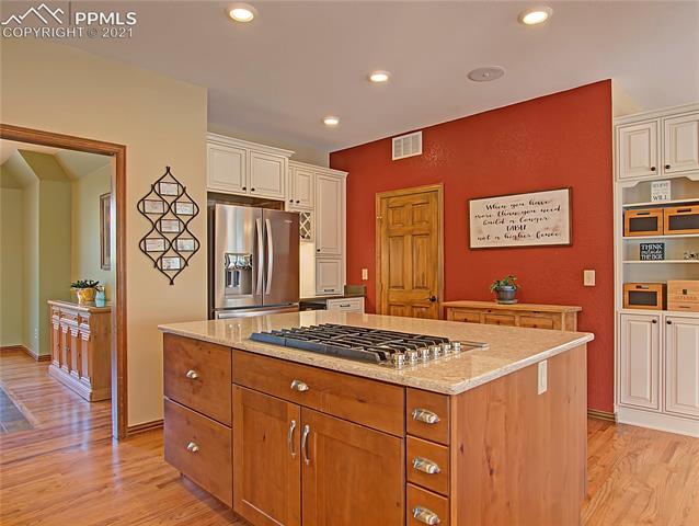 735 Winding Hills Road Monument, CO 80132 - Photo 7 of 42 6 gas burner cooktop in the island...door leads to the laundry room.