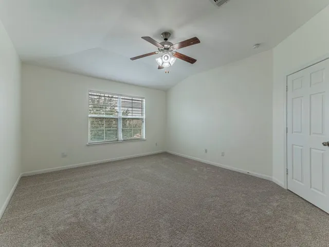 a view of an empty room and chandelier fan