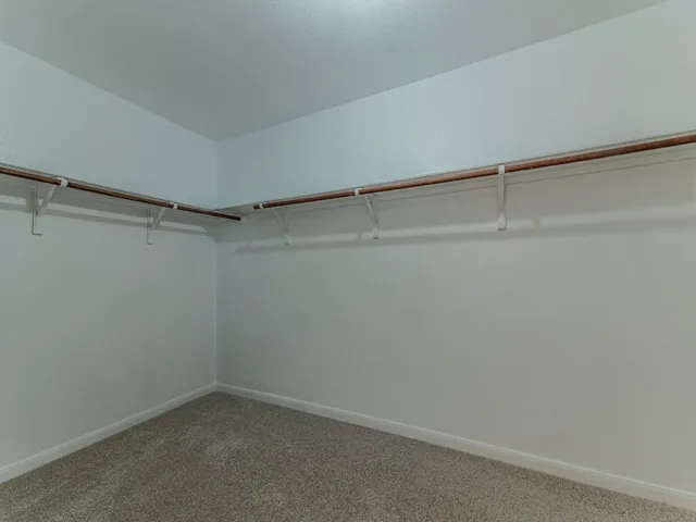 an empty room with a chandelier fan and windows