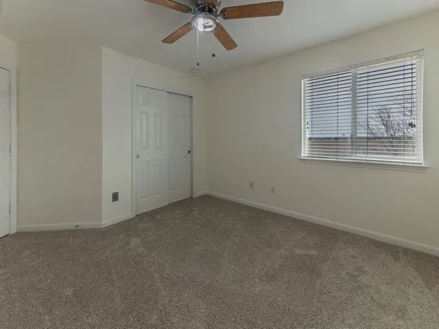 an empty room with a ceiling fan and a window