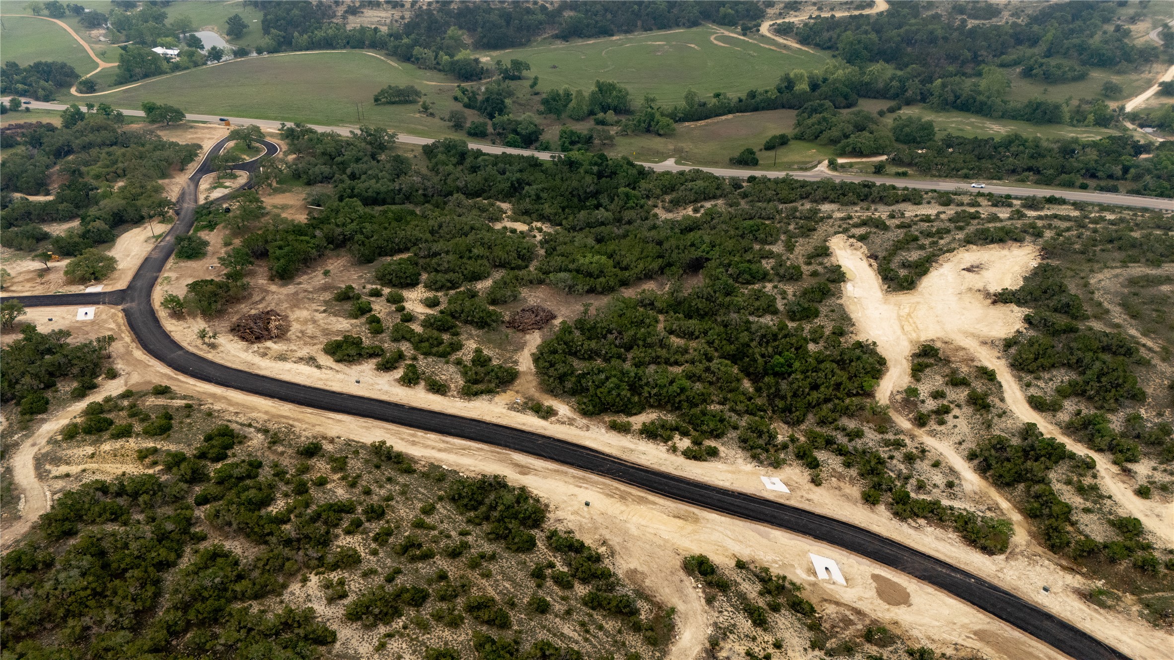 Lot 3 Ranch Road 165 Dripping Springs, TX 78620 - Photo 5 of 11 Aerial perspective showcasing a newly paved road winding through varied terrain