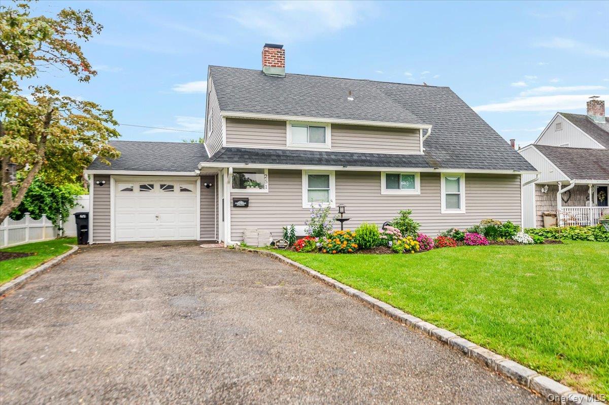 View of front of property with roof with shingles, driveway, a chimney, and a garage