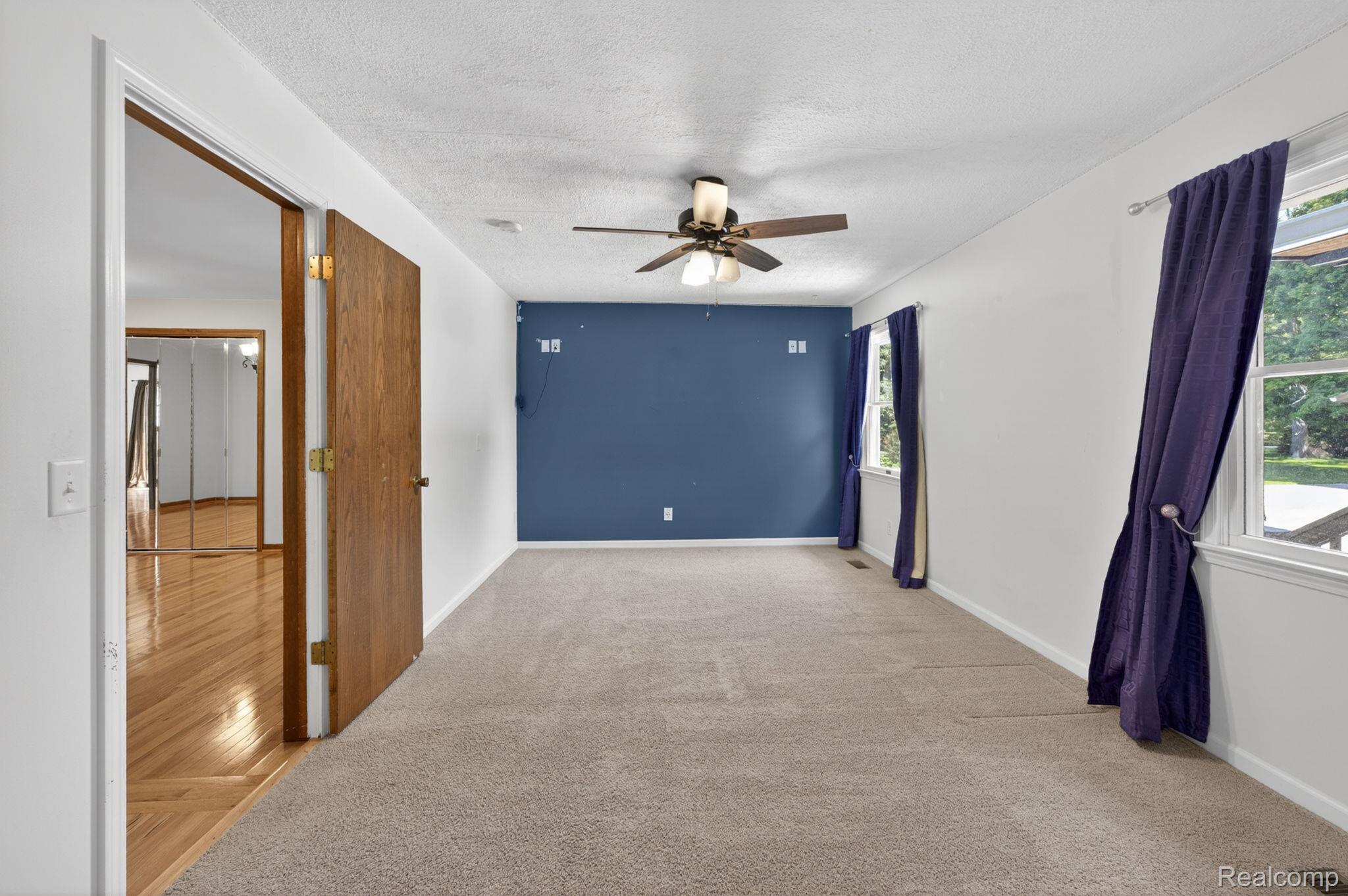 9353 Hill Road Swartz Creek, MI 48473 - Photo 37 of 98 Spacious room featuring neutral carpet, a ceiling fan with integrated lighting, and a prominent accent wall