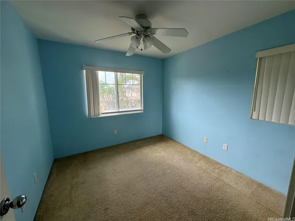 an empty room with a chandelier fan and windows