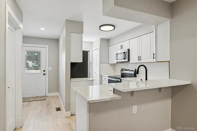 a kitchen with stainless steel appliances granite countertop a sink a stove and a refrigerator