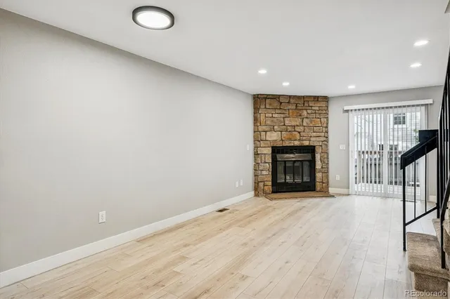 a view of an empty room with wooden floor and a fireplace