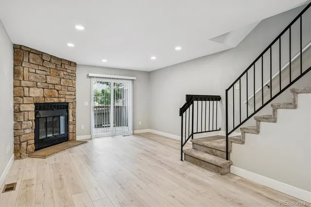 a view of an empty room with wooden floor fireplace and a window