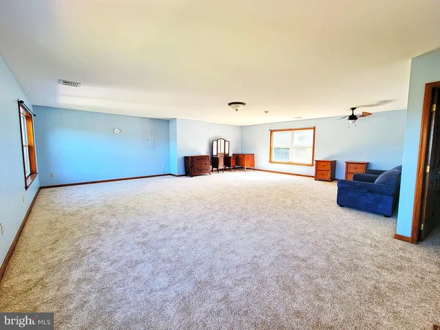 an empty room with windows and ceiling fan