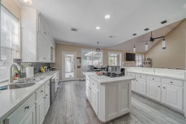 a kitchen with white cabinets sink and stove