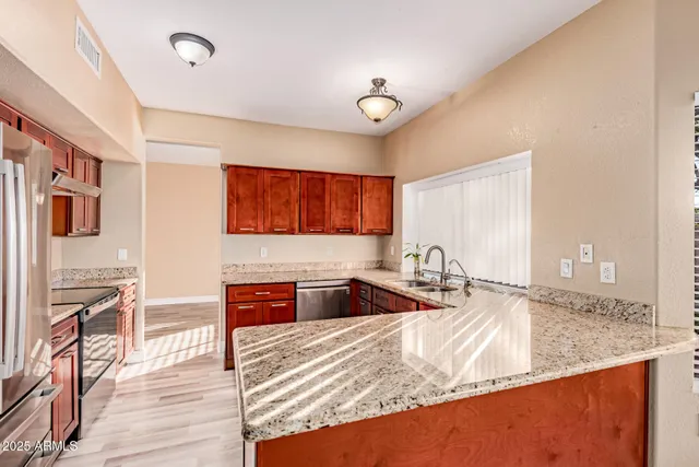 a kitchen with stainless steel appliances granite countertop a sink stove and wooden cabinets