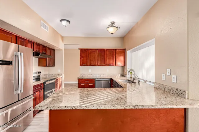 a kitchen with stainless steel appliances granite countertop a sink a stove and a refrigerator