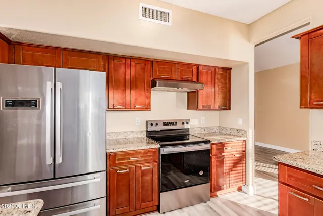 a kitchen with stainless steel appliances granite countertop a refrigerator and a stove
