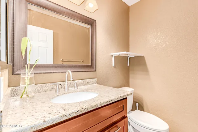 a bathroom with a granite countertop sink vanity mirror and toilet