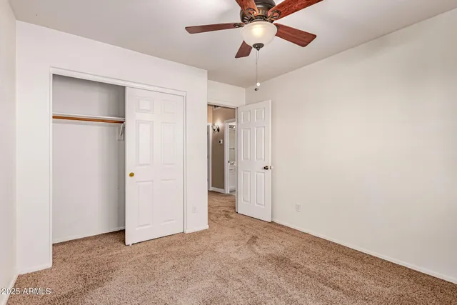 an empty room with closet and a chandelier fan
