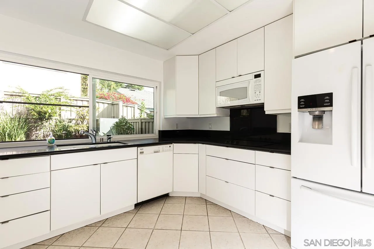 8065 Caminito Gianna La Jolla, CA 92037 - Photo 12 of 27 a kitchen with granite countertop white cabinets white appliances a sink and a large window