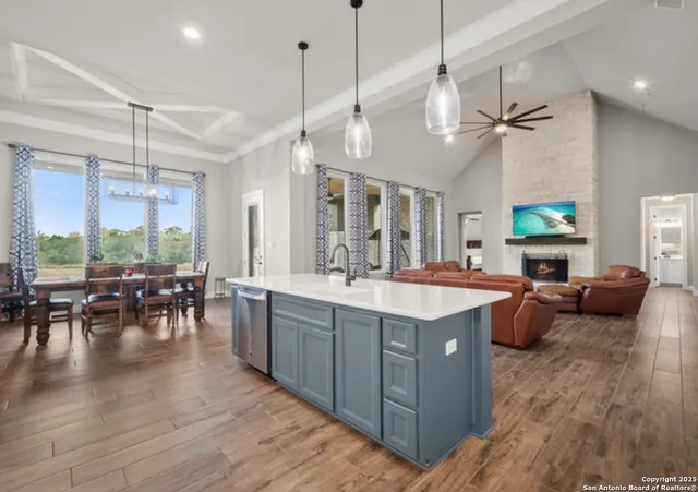 a large kitchen with lots of counter space a sink appliances and living room view
