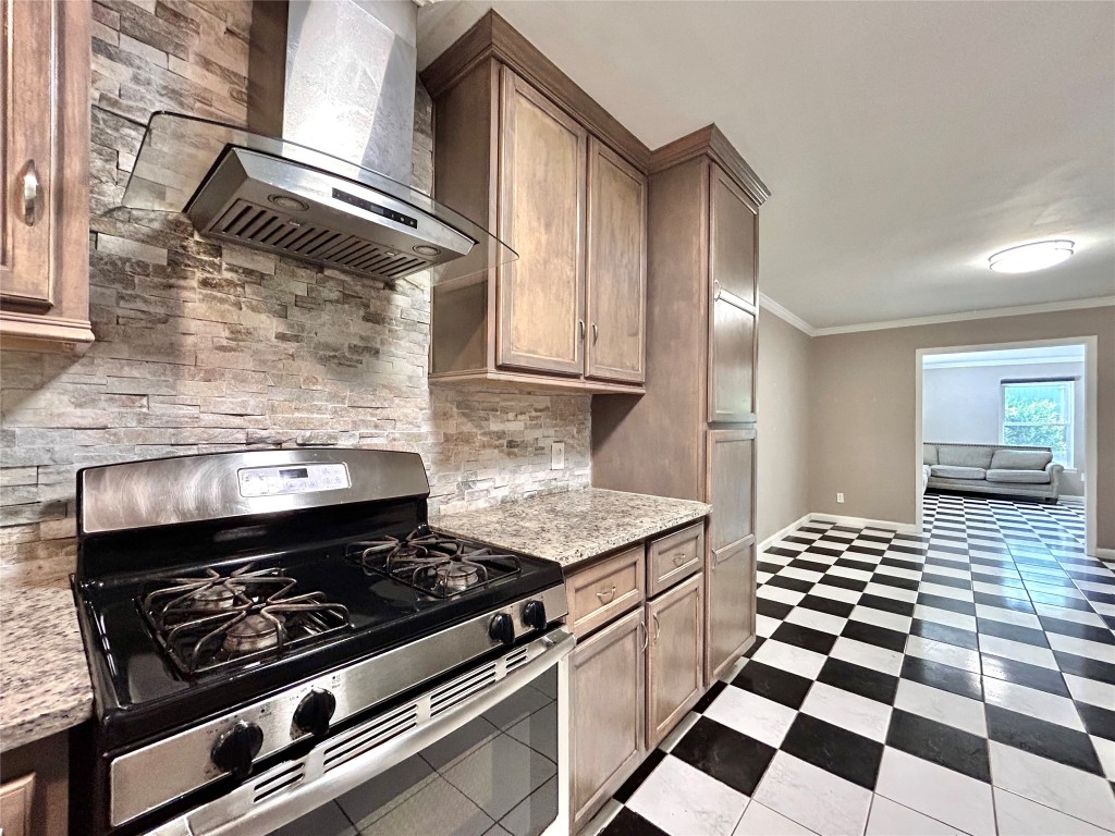 2309 Devonshire Drive, Unit A Austin, TX 78723 - Photo 14 of 39 Kitchen with wall chimney range hood, stainless steel gas stove, light stone counters, ornamental molding, and backsplash