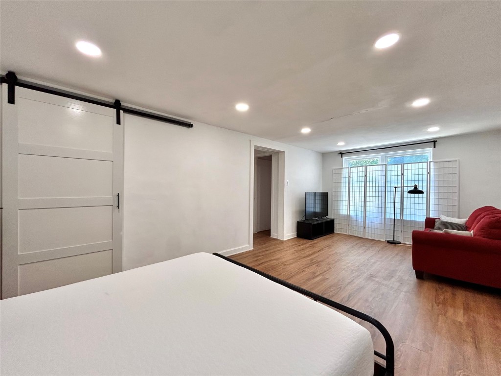 2309 Devonshire Drive, Unit A Austin, TX 78723 - Photo 31 of 39 Bedroom with a barn door, wood finished floors, and recessed lighting