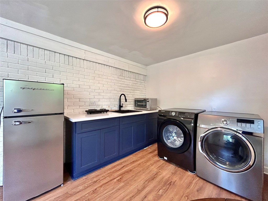 2309 Devonshire Drive, Unit A Austin, TX 78723 - Photo 38 of 39 Washroom featuring light wood-type flooring, washing machine and dryer, and brick wall