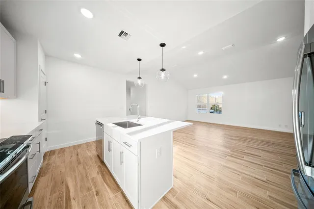 a kitchen with a sink stove and wooden floor