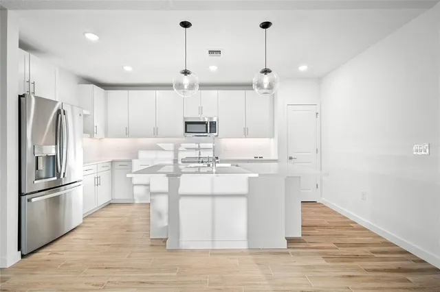 a kitchen with kitchen island white cabinets and stainless steel appliances