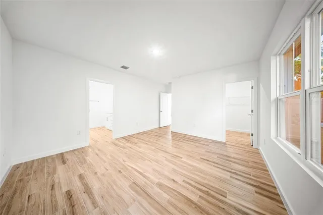 a view of empty room with wooden floor and fan