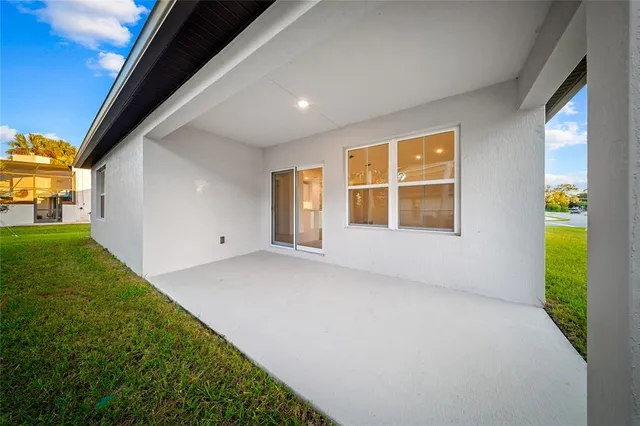 a view of an empty room with a window and kitchen view