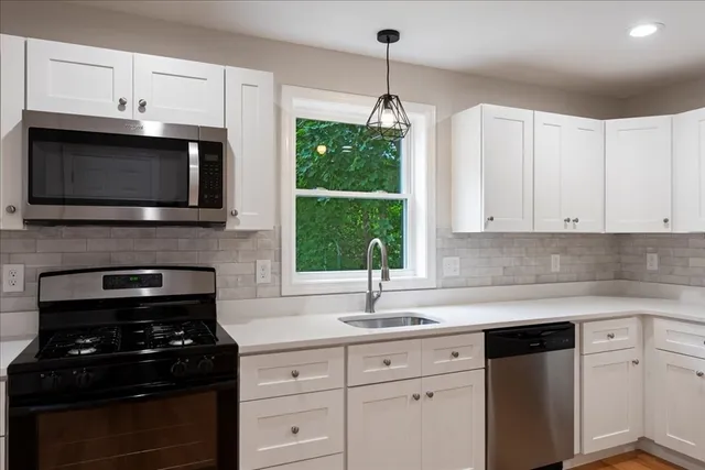 a kitchen with granite countertop white cabinets and black appliances