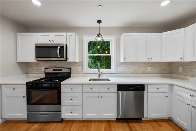 a kitchen with white cabinets stainless steel appliances and a window