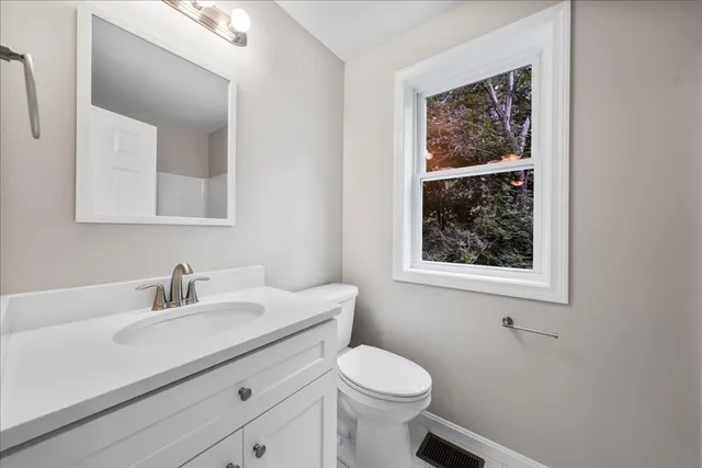 a bathroom with a toilet sink vanity and mirror