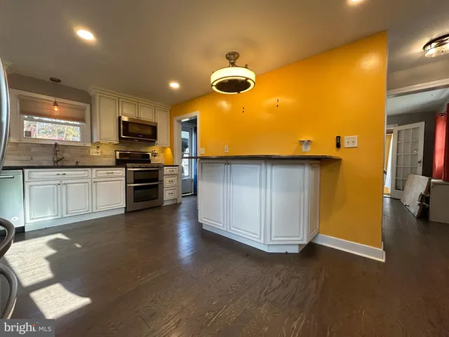 a kitchen with stainless steel appliances a stove a sink a microwave a refrigerator and cabinets