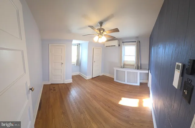 a view of empty room with wooden floor and fan