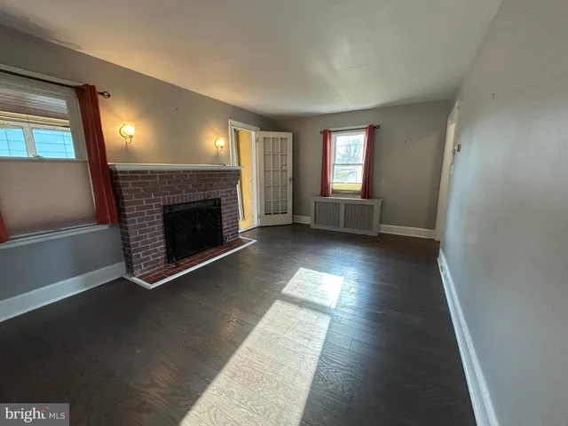 an empty room with wooden floor fireplace and windows