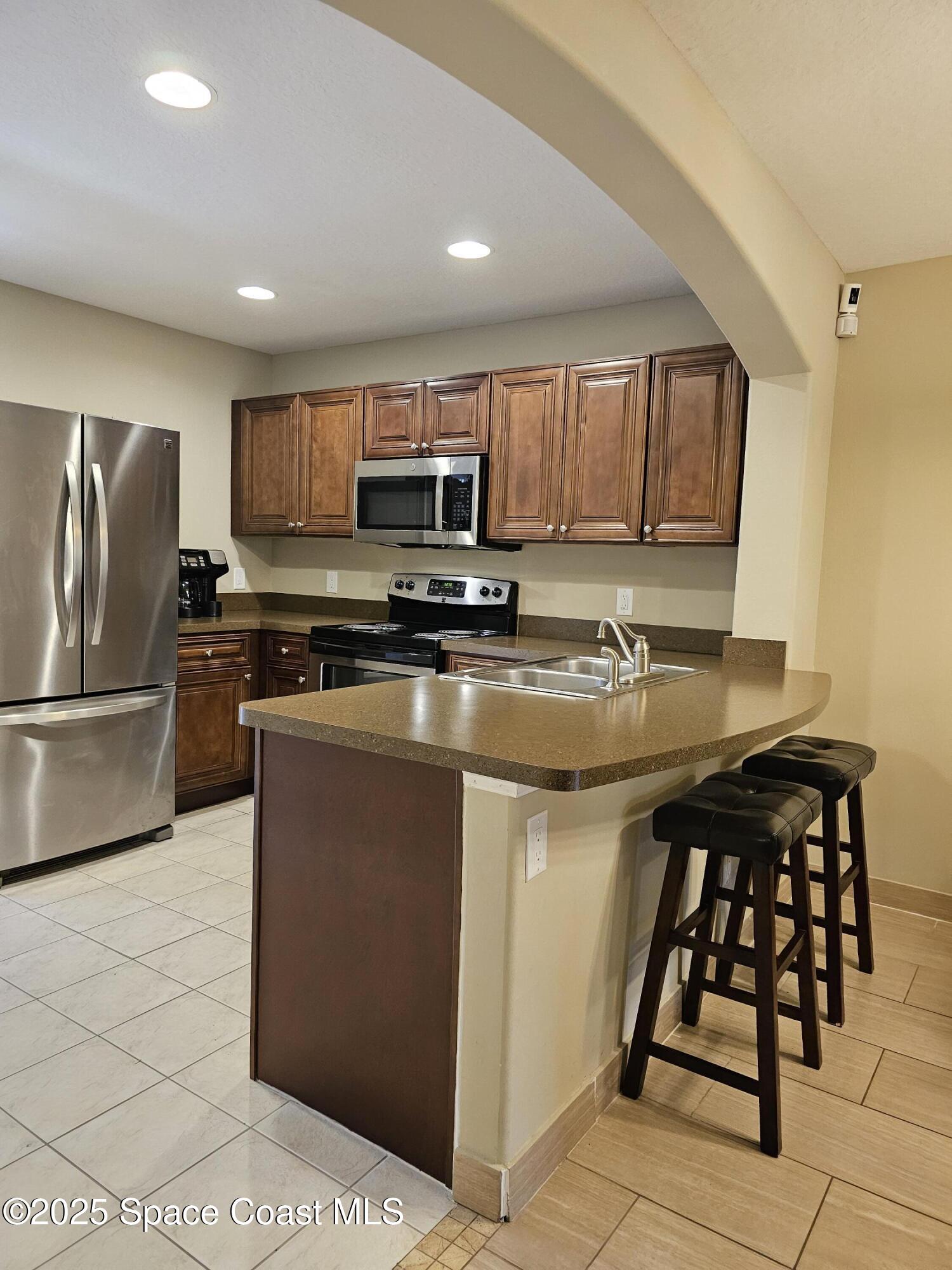 4570 Radiant Way, Unit 104 Melbourne, FL 32901 - Photo 8 of 41 a kitchen with stainless steel appliances a stove a sink a microwave a refrigerator and cabinets