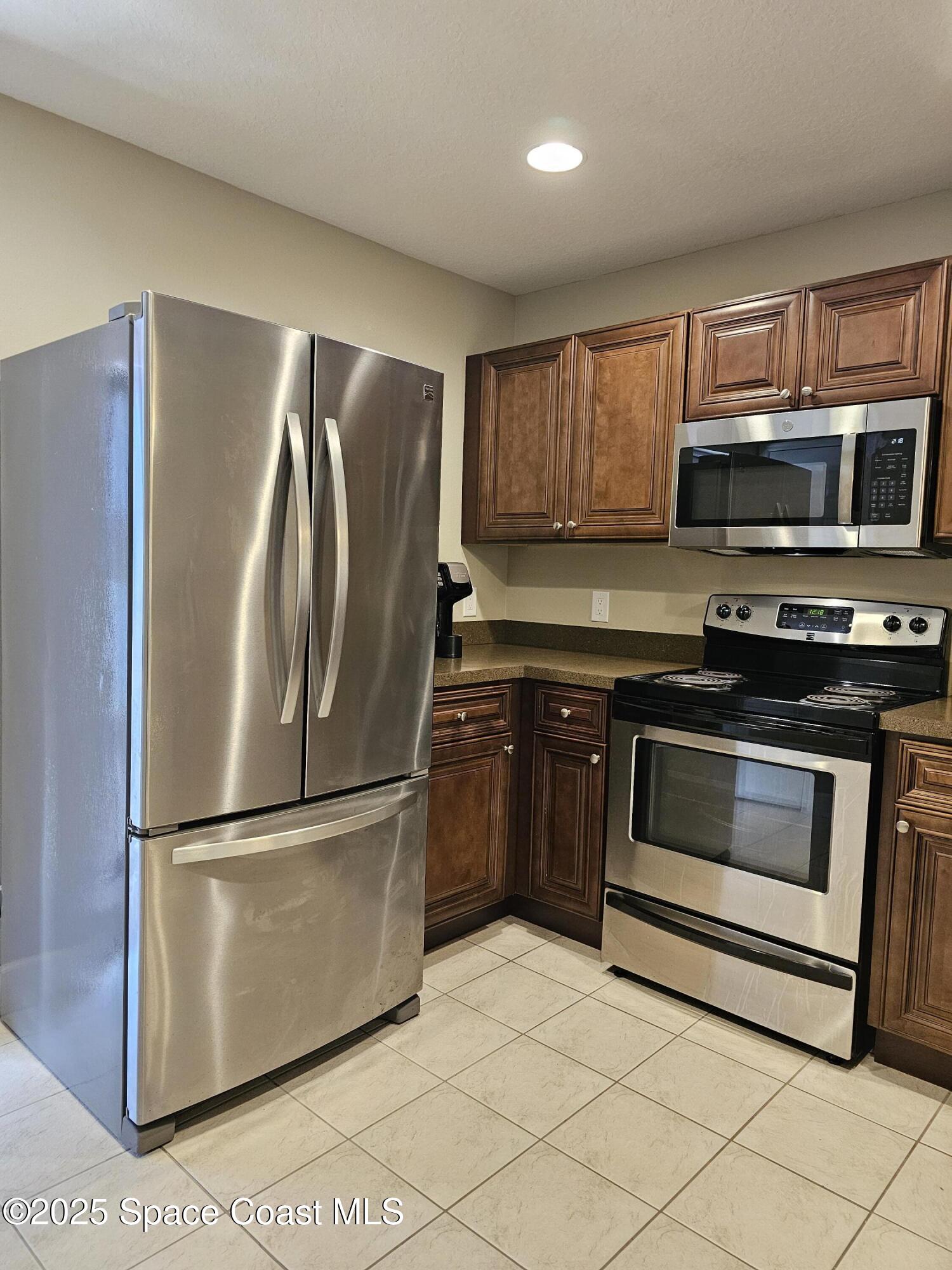 4570 Radiant Way, Unit 104 Melbourne, FL 32901 - Photo 9 of 41 a kitchen with granite countertop a refrigerator stove and microwave