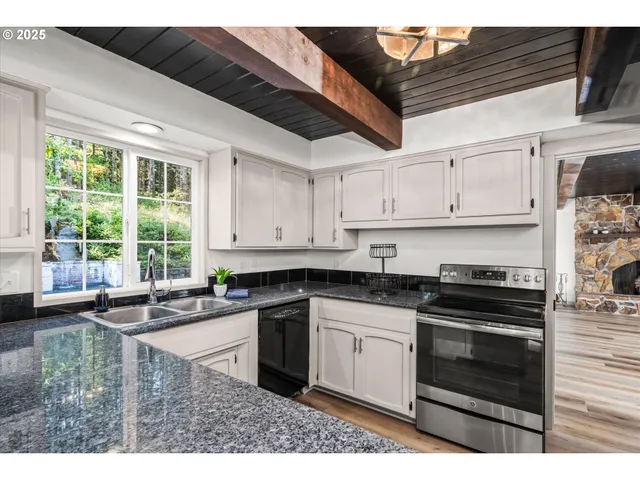 a kitchen with granite countertop a sink and white cabinets