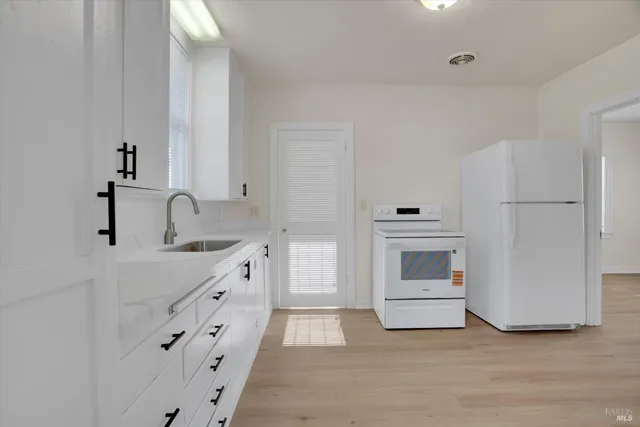 a kitchen with granite countertop white cabinets and white appliances