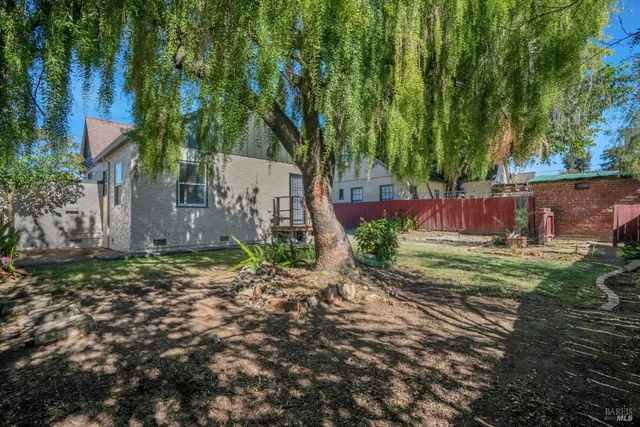a view of a yard with a house and trees in the background