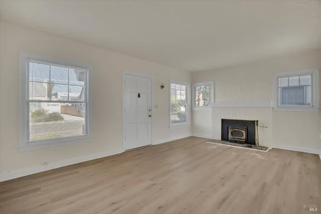 an empty room with windows and fireplace