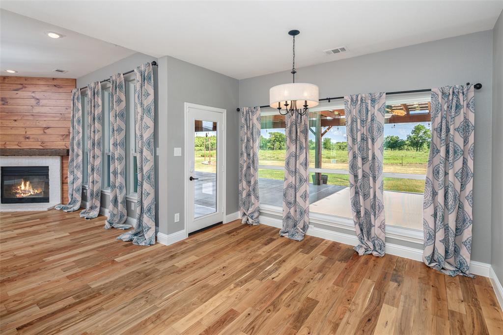 1019 Vaughan Lane Tioga, TX 76271 - Photo 18 of 40 Spacious interior featuring wood-finish flooring, a contemporary fireplace with a wood mantle and shiplap accent wall, and multiple large windows