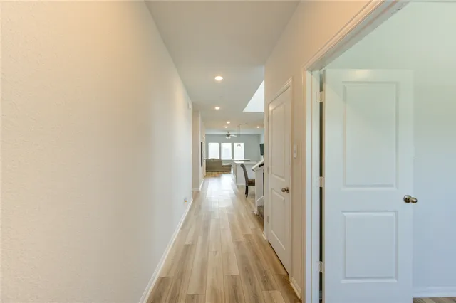 a view of a hallway with wooden floor and a bathroom