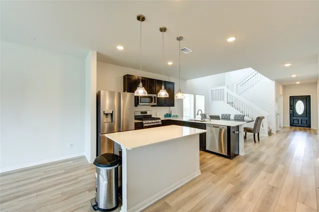 a large kitchen with stainless steel appliances a large counter top a sink a stove and a refrigerator