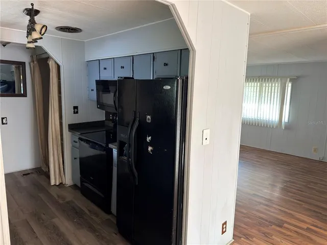 a kitchen with stainless steel appliances a refrigerator and a wooden floor