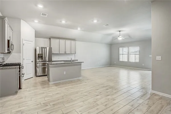 a kitchen with granite countertop a refrigerator and a stove top oven