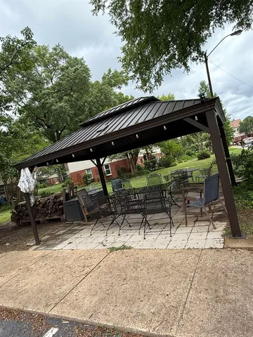 a backyard of a house with table and chairs under an umbrella