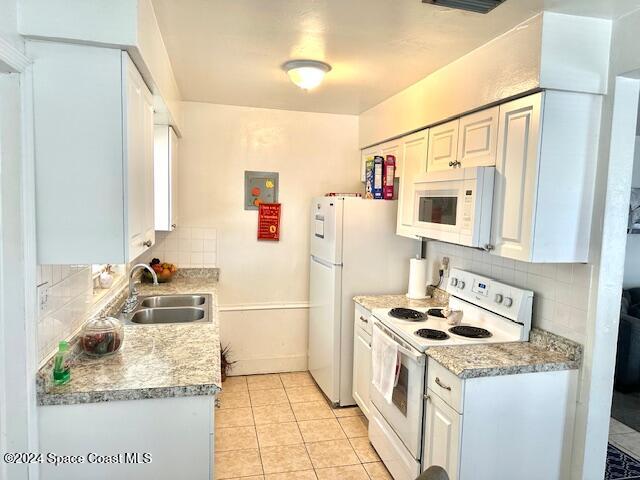 941 Croton Road Melbourne, FL 32935 - Photo 25 of 26 a kitchen with refrigerator a stove a sink and white cabinets with wooden floor